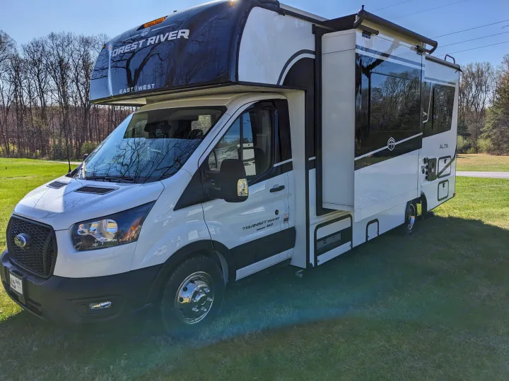 White and black Forest River Alita Class C RV rental with its slide-out extended, parked on grass for your adventure.. East to West Alita 2025