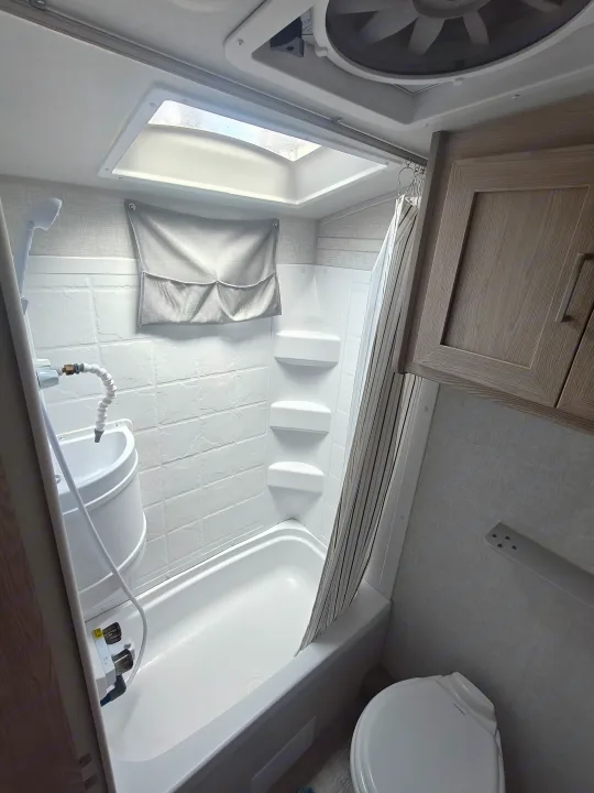 Inside an RV rental bathroom: features a compact shower/tub, sink, toilet, and overhead vent fan with a skylight.. Geopro 19Bh 2021