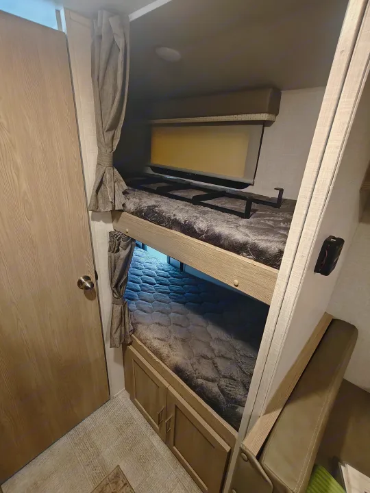 This RV rental interior features spacious bunk beds with comfy bedding, a ladder, and privacy curtains, perfect for family adventures.. Geopro 19Bh 2021