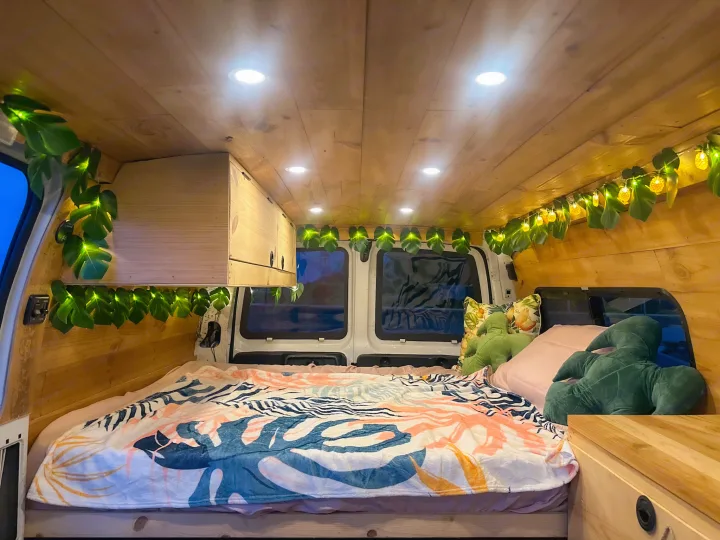 Cozy RV rental interior: wood-paneled, with recessed lights, tropical blanket, and charming leaf/pineapple string lights.. Chevrolet Express 1999