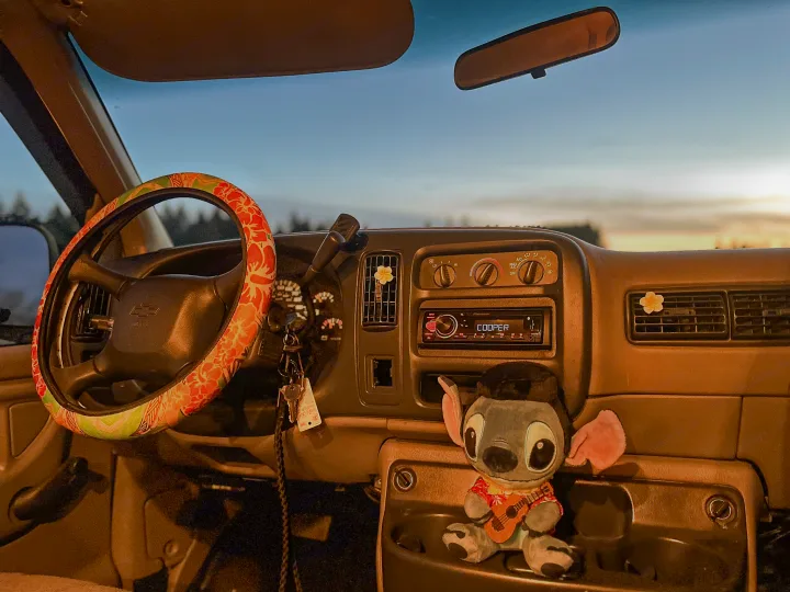 Cozy RV rental interior at dusk: floral steering wheel, Stitch plush, & keys ready for adventure.. Chevrolet Express 1999