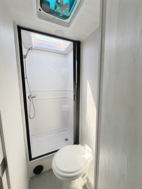 Clean, modern RV rental bathroom with a compact shower, skylight, and toilet for comfortable travel.. East to West Entrada 210NS 2025