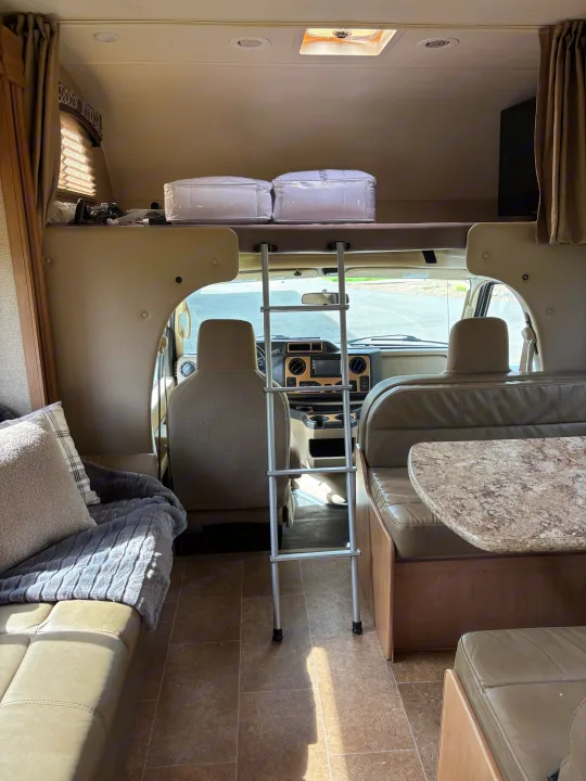 Spacious RV rental interior featuring an over-cab bunk, dinette, and living area with comfortable seating.. Thor Chateau 2019