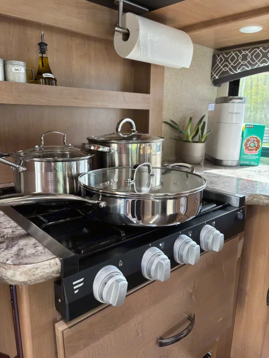 RV rental kitchen: stainless steel pots on a compact stovetop, plus coffee maker and paper towels.. Thor Chateau 2019