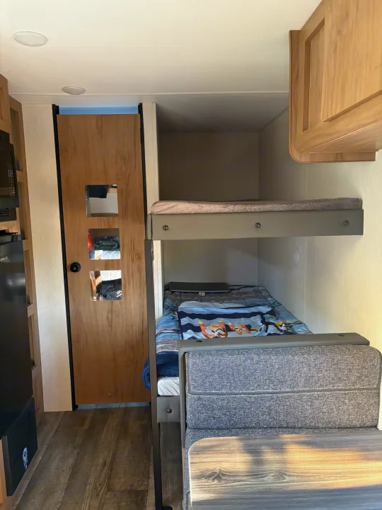 Cozy RV rental interior featuring bunk beds, a dinette, and compact kitchen. Ideal for family road trips.. Forest River Cherokee Wolf Den 16EV 2024