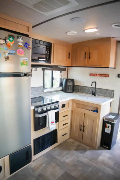 RV rental kitchen with stainless fridge, microwave, oven, sink, & air fryer. Features light wood cabinets & sleek design.. Cruiser RV Radiance Ultra Lite 2020