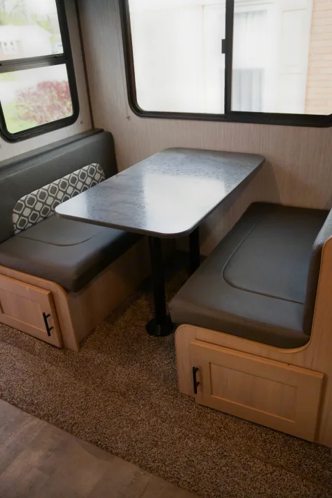 Enjoy comfort in your RV rental with this dinette featuring gray cushioned benches, a sturdy table, and storage cabinets.. Cruiser RV Radiance Ultra Lite 2020