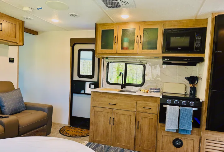 Modern RV rental kitchen and living area, with comfortable seating, a well-equipped kitchen, and natural light.. Forest River Coachmen Freedom Express 2025
