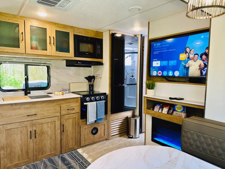 Modern RV rental interior with a full kitchen, TV, fireplace, and dining area.. Forest River Coachmen Freedom Express 2025