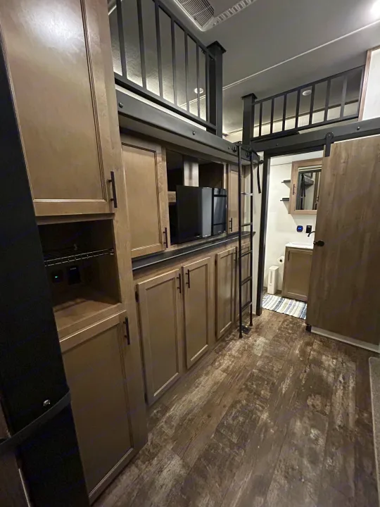 RV rental interior: modern kitchen/storage, TV, ladder to loft bunk, & bathroom.. Forest River Sabre 2022
