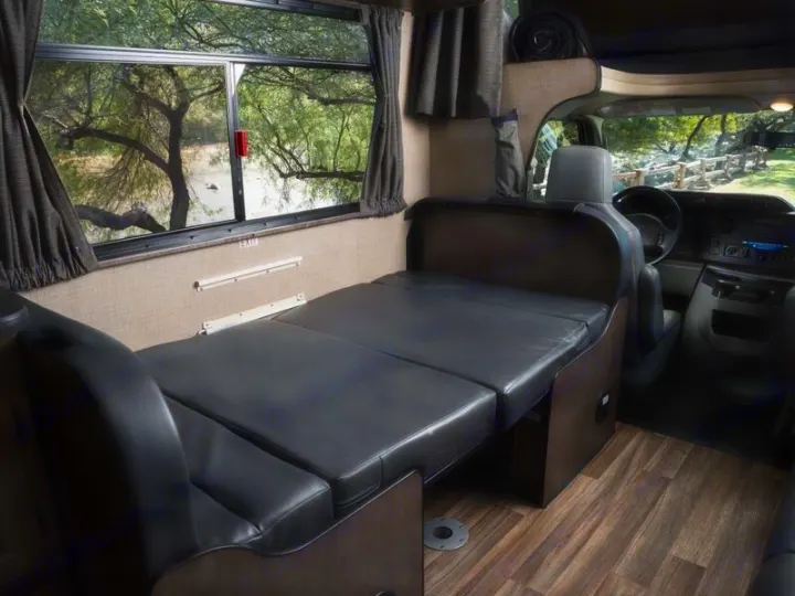 This rv rental interior features a comfy convertible bed, large window with a beautiful nature view, and a driver's cockpit.. Thor Majestic 2019