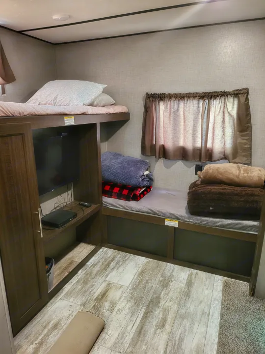 Cozy RV rental bunk room features stacked beds, a TV, and storage for a comfortable travel stay.. Crossroads RV Zinger 2020