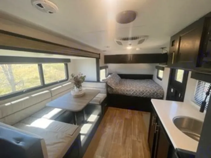 Cozy and modern RV rental interior, featuring a dining booth, comfortable bed, and compact kitchen—ideal for road trips.. Forest River Cherokee Wolf Pup 2023