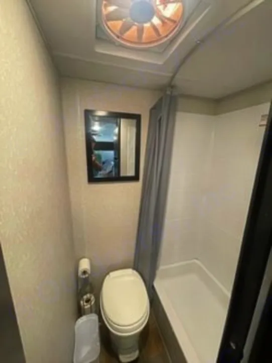 This RV rental's compact RV bathroom features a toilet, standing shower, and mirror.. Forest River Cherokee Wolf Pup 2023