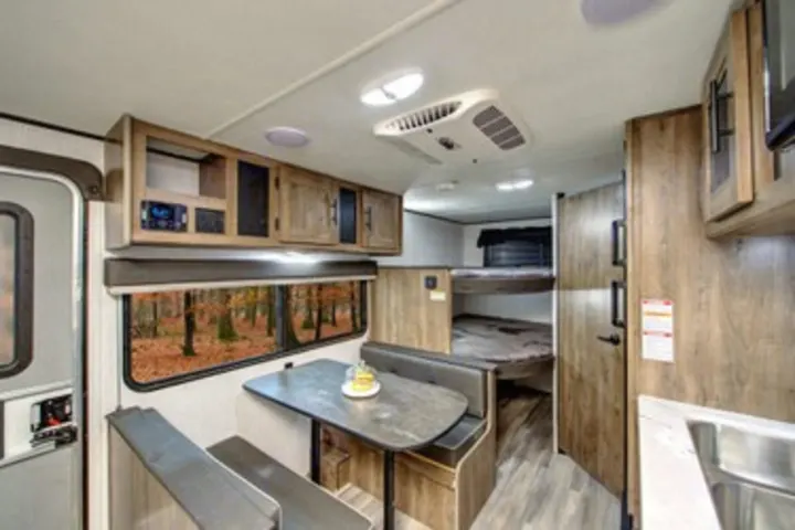 Cozy RV rental interior with dining booth, bunk beds, and kitchen, perfect for your next road trip adventure.. Heartland RVs Pioneer 2022