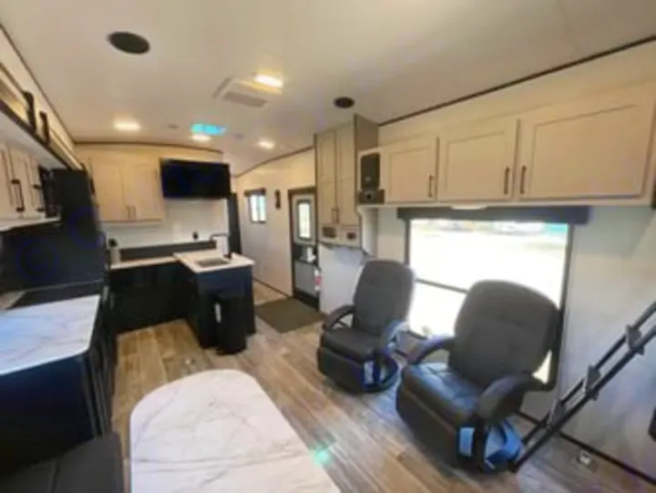 Spacious RV rental interior featuring a modern kitchen, comfy recliners, and a dining area, all with wood-look flooring.. Heartland RVs Fuel Toy Hauler 2022