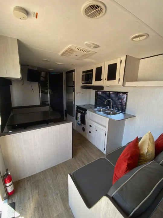 This RV rental interior features a full kitchen, dinette, and living area, offering a comfortable space for travel.. Heartland Trail Runner 2021