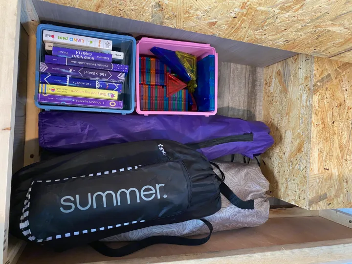 RV rental storage with children's books, magnetic tiles, and gear, neatly organized for travel.. Coleman Lantern 17B 2024