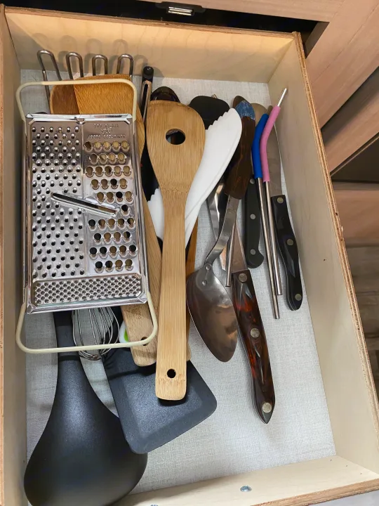 RV rental kitchen drawer: a neat array of cooking utensils including grater, spatulas, and knives.. Coleman Lantern 17B 2024