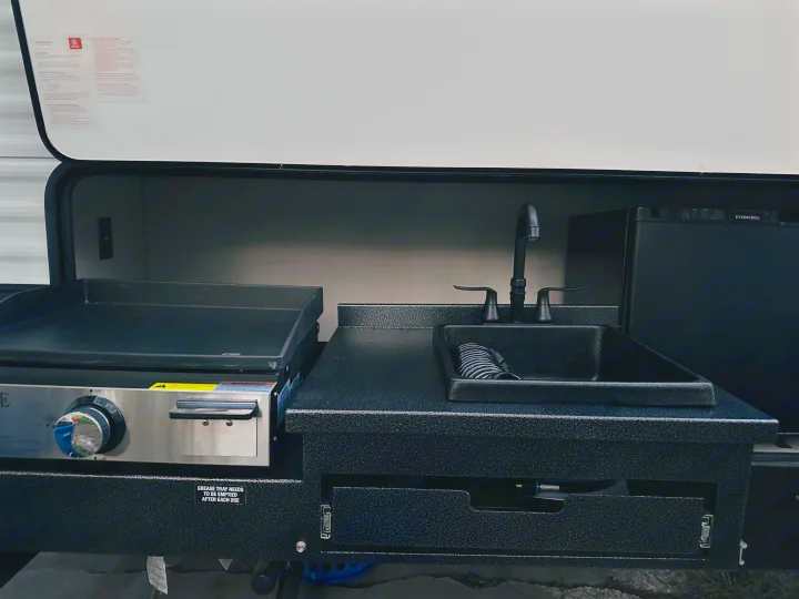 This RV rental features a full outdoor kitchen: griddle, sink, and EVERCHILL mini-fridge for easy camping meals.. PALOMINO 28BHSS 2024