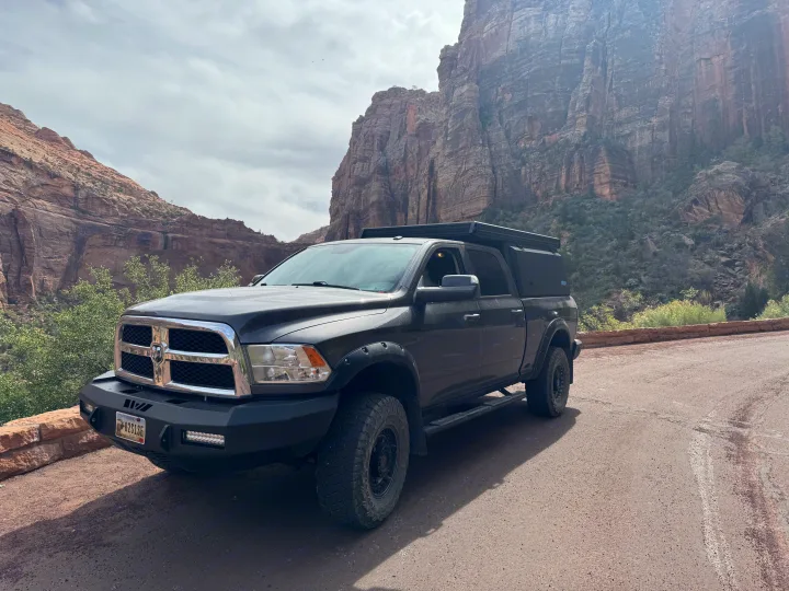 Dark grey overland truck with pop-top camper in a mountainous park setting. Ideal for adventure travel, a great alternative to an RV rental.. Dodge Dodge 1 Ton Pu 2018