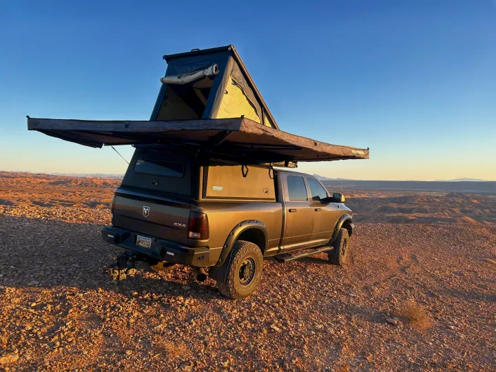 An overland truck with rooftop tent and awning deployed on a rocky desert overlook, perfect for an adventurous RV rental trip.. Dodge Dodge 1 Ton Pu 2018