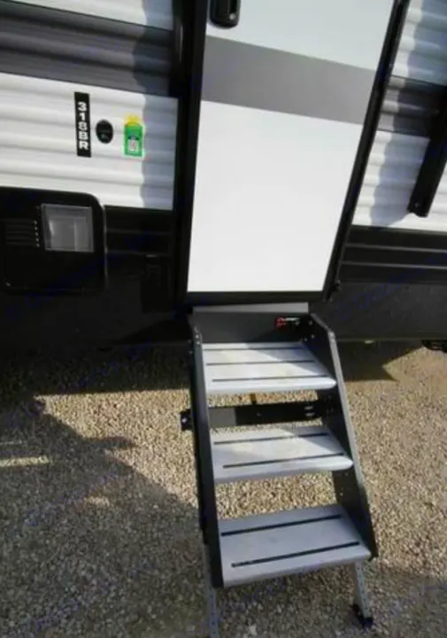 This RV rental features an open entry door and sturdy four-step stairs extended to the gravel ground, ready for use.. Keystone RV Hideout 2023