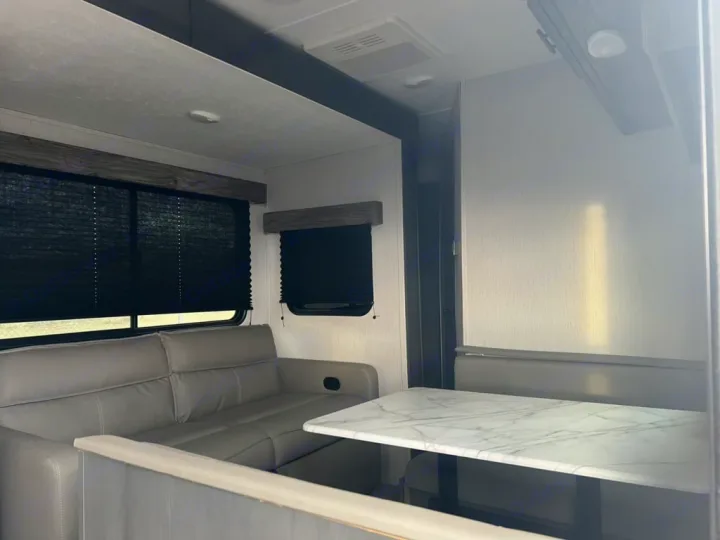 Modern RV rental interior with a comfy sofa, window shades, and a dining area, offering a home-like feel on the road.. Aspen Trail Aspen Trail Trailer 2021