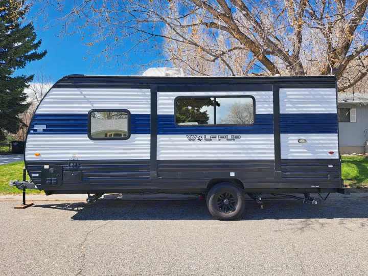 Side view of a white, blue, and black Wolf Pup travel trailer, a. Forest River Cherokee Wolf Pup 2023