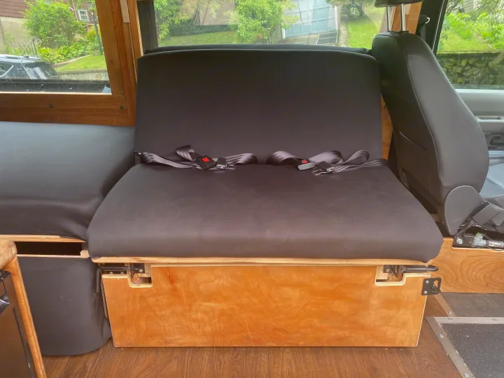 Inside an RV rental: A sturdy wooden bench with black cushions & seatbelts provides comfortable passenger seating.. Ford Econoline 2011