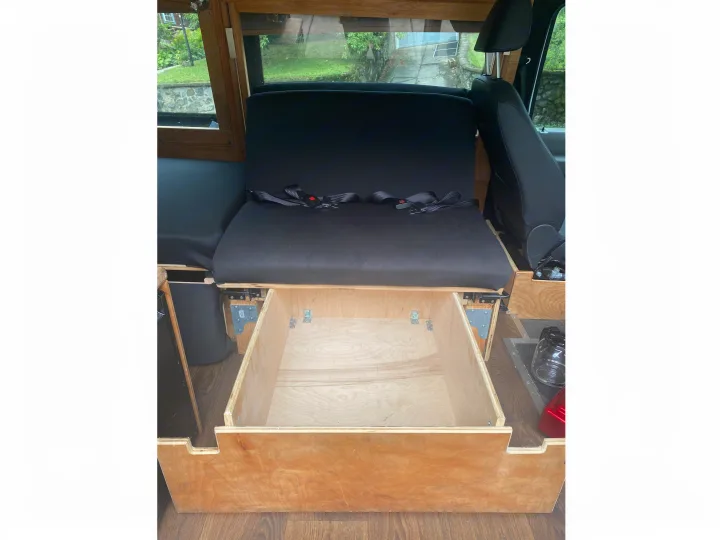 RV rental: Open wooden drawer beneath black padded seating with seatbelts, offering a glimpse of the outdoor scenery.. Ford Econoline 2011