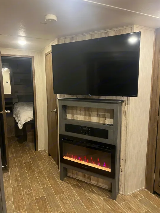 RV rental interior: cozy living space with a large TV, electric fireplace, and bedroom beyond.. Forest River Palomino Puma 2021