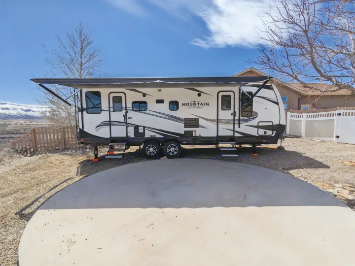 Mountain Series RV rental, parked with awning extended, showcases distant mountains and a residential setting.. Outdoors RV Timber Ridge 2022