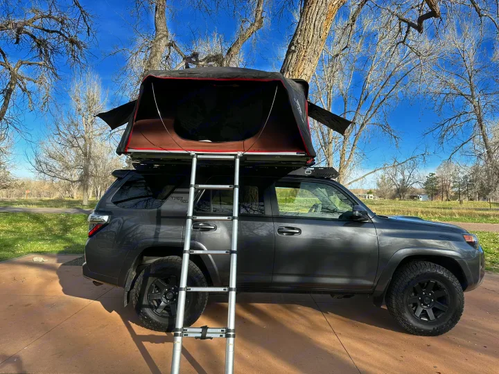 Adventure-ready grey SUV with rooftop tent & ladder setup. A unique RV rental alternative for camping trips.. Toyota 4Runner TRD OffRoad 2020