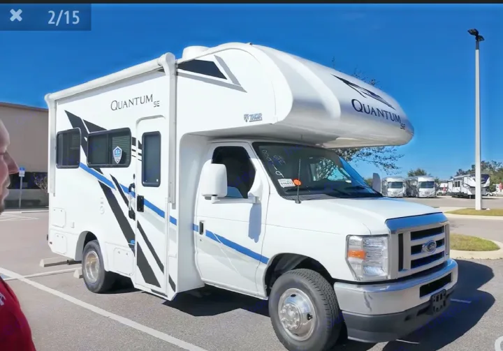 White Thor Quantum SE Class C RV rental is seen. This motorhome, with blue and black graphics, is parked on a sunny lot.. THOR THOR QUANTUM LC19 2025