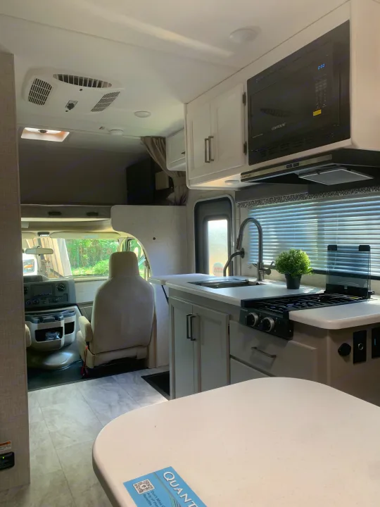 Spacious RV rental interior featuring a modern kitchen, overhead bunk, and cockpit for comfortable travel.. THOR THOR QUANTUM LC19 2025