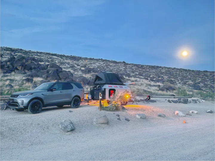 Night camping setup: SUV, off-road RV rental, and rooftop tent under a full moon in a rocky landscape.. Mammoth Overland Mammoth HV 2023