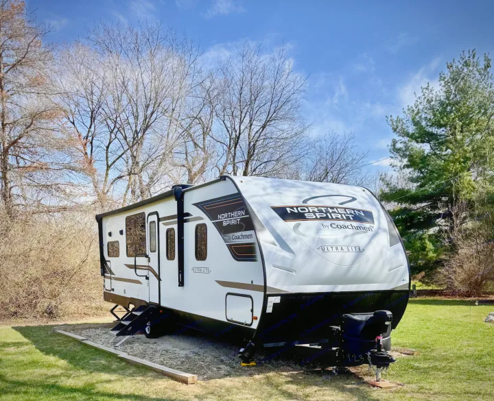 RV rental: A white Northern Spirit travel trailer parked on a gravel pad in a sunny campsite.. Forest River Coachmen Northern Spirit Ultra Lite 2023