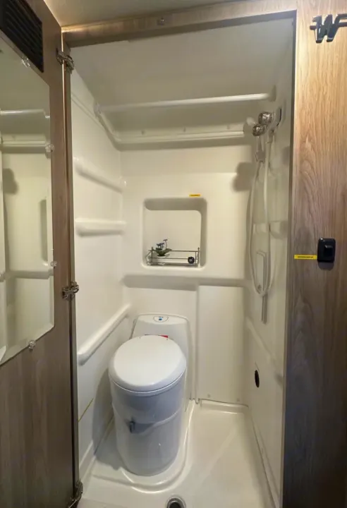 RV rental wet bath interior: compact shower/toilet combo in white molded plastic.. Winnebago Solis 2023