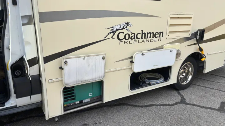 Side view of a Coachmen Freelander RV rental with open storage bays revealing a generator and coiled hose.. Forest River Coachmen Freelander Micro 2018