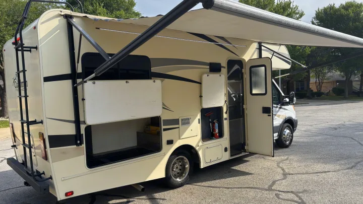 Beige Coachmen Freelander rv rental with open compartments, extended awning, and illuminated LED lights, parked on asphalt.. Forest River Coachmen Freelander Micro 2018