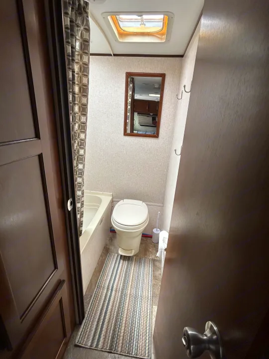 Inside an rv rental: a compact bathroom with a toilet, small tub/shower, vanity mirror, and ceiling skylight, ready for your trip.. Jayco Jay Flight SLX Baja Edition 2017
