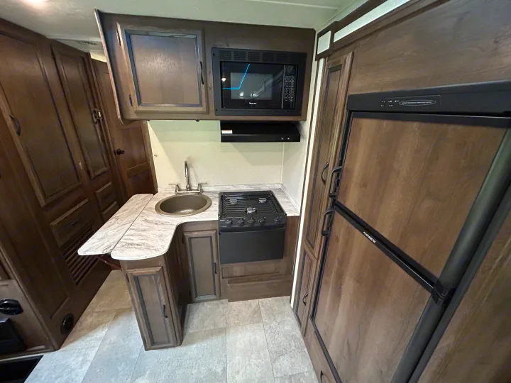 This RV rental offers a well-equipped kitchen: microwave, sink, stovetop, and Dometic refrigerator for travelers.. Coachman Freelander 26DS 2019