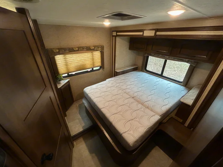 Spacious RV rental bedroom featuring a comfortable bed, ample storage, and large windows, ideal for travel.. Coachman Freelander 26DS 2019