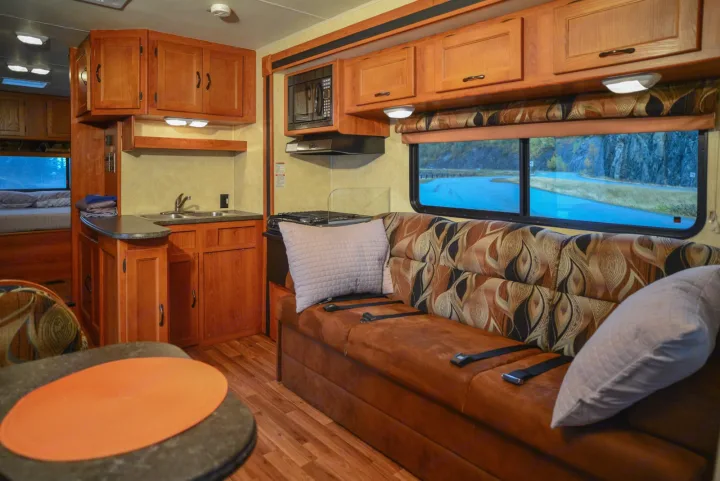 RV rental interior: equipped kitchen, comfortable living area with a scenic window view, and bedroom. Ideal for road trips.. Forest River Coachmen Freelander 2014