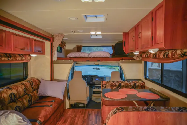 Spacious RV rental interior with a comfy bed, dining area, and sofa, showcasing ample room for road trips.. Forest River Coachmen Freelander 2014