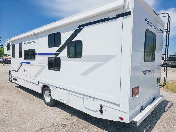 White Four Winds RV rental, side view, showing black/blue/gray graphics, multiple windows, and storage.. Thor Motor Coach Four Winds 2026