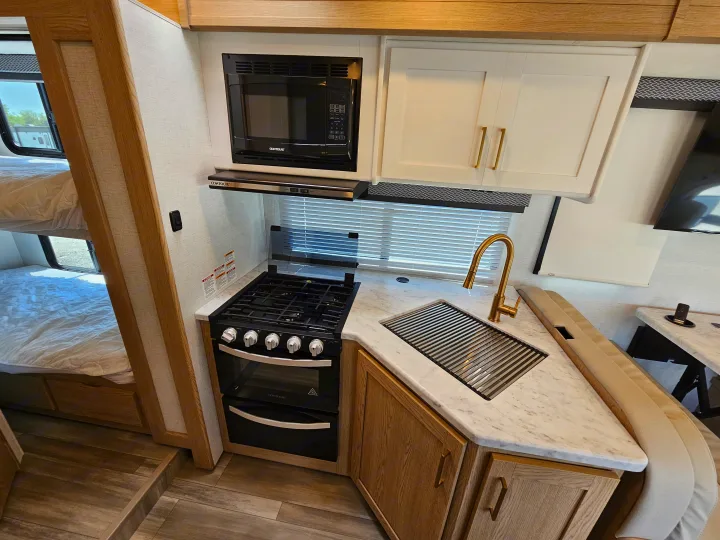 This RV rental offers a well-equipped kitchen with a stove, microwave, sink, and comfortable bunk beds for travel.. Thor Motor Coach Four Winds 2026