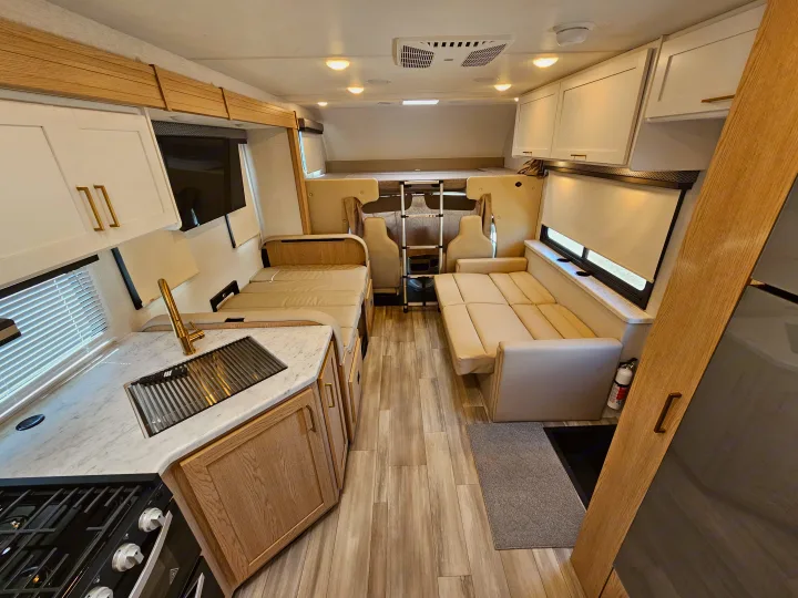 Bright rv rental interior showing a full kitchen, convertible dinette, and cozy overhead bed area.. Thor Motor Coach Four Winds 2026