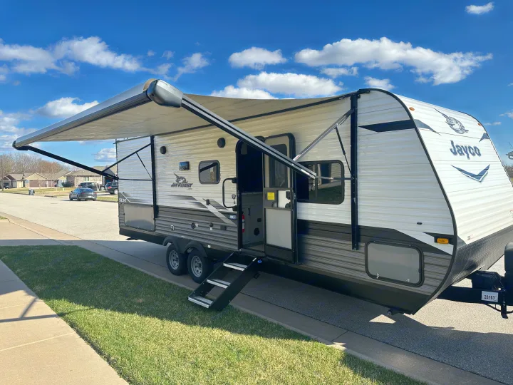 White & gray Jayco travel trailer RV rental parked on a sunny street with its awning out.. Jayco Jay Flight SLX 2022